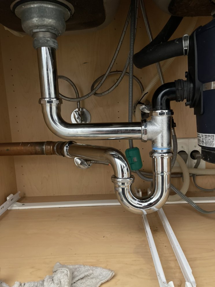Completed sink drain and garbage disposal installation under a kitchen sink